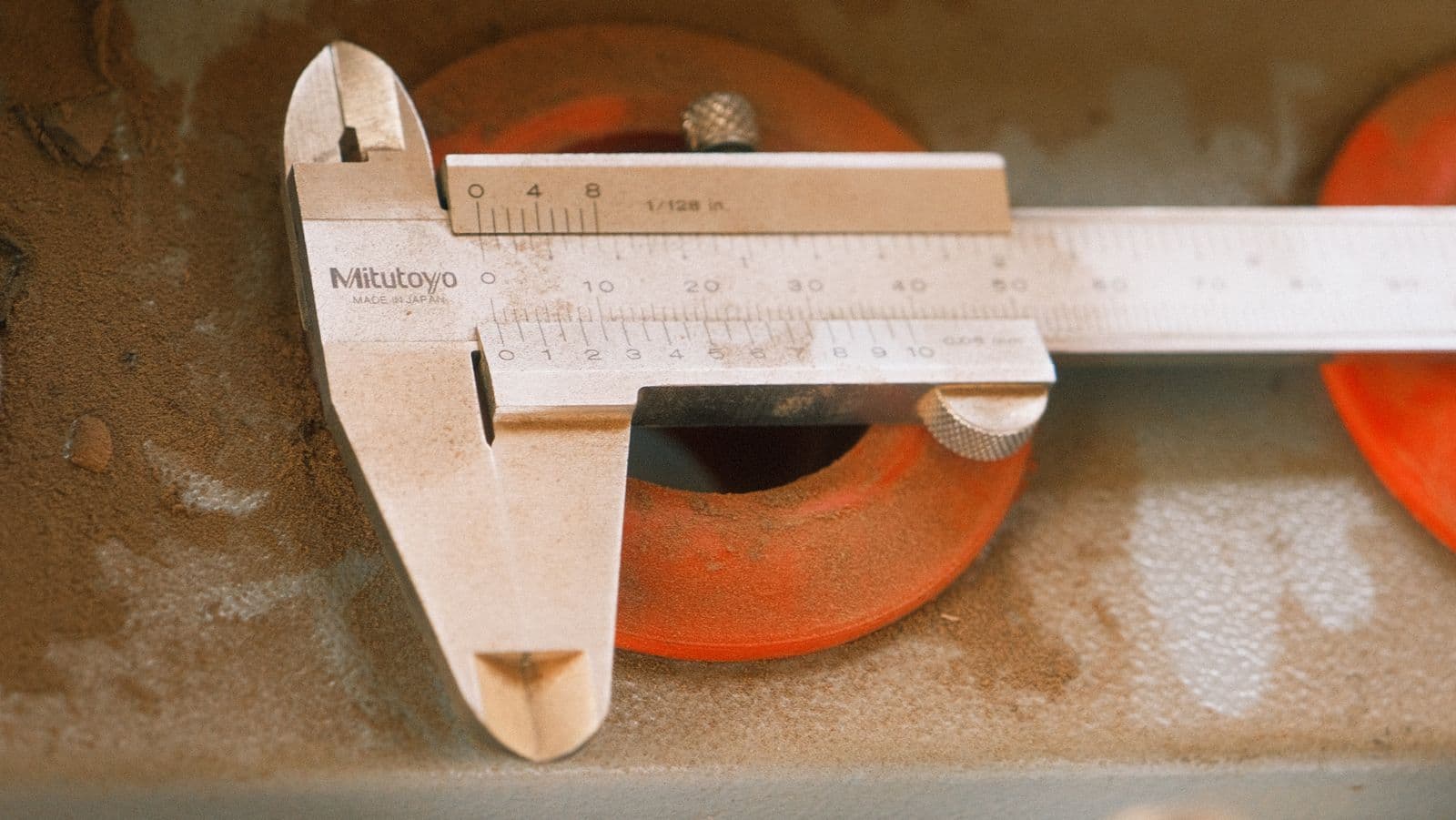 Mitutoyo vernier caliper measuring the bore of a machined part on a workshop surface