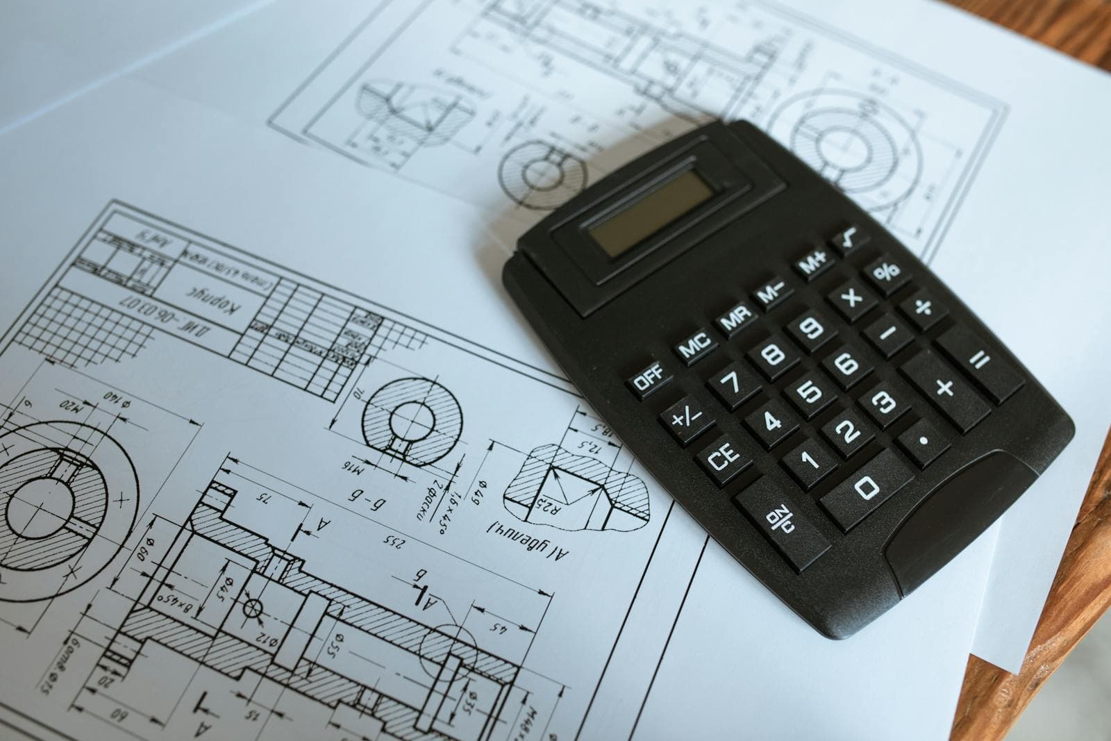 Toleranced mechanical engineering drawings of shaft components with section views, thread callouts and a calculator on top