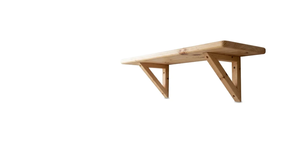 A pine wall shelf on angled brackets, photographed on white